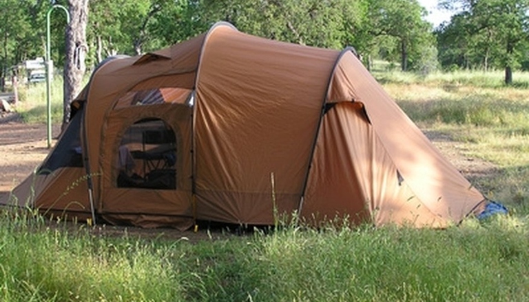 A tent is a temporary structure made of fabric and poles, used for camping or as a temporary shelter.